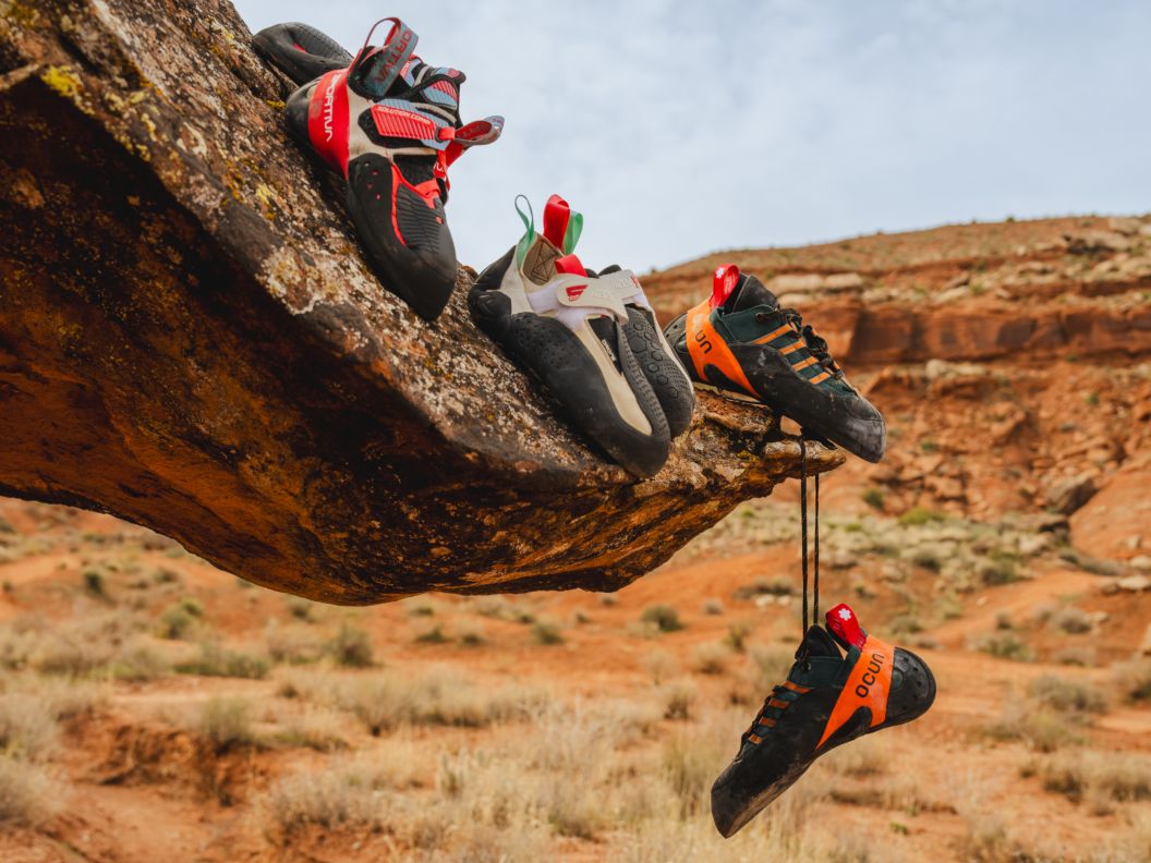 Three pairs of climbing shoes on top of a rock.